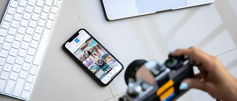 Eine Kamera fotografiert digitale Geräte (Smartphone, Laptop, Tastatur)